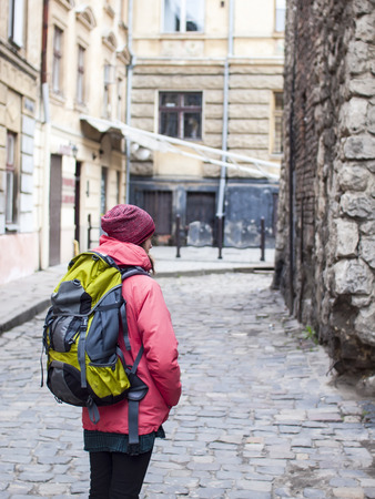 A lonely girl with a backpack walking around the old town.の写真素材