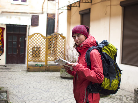 A lonely girl with a backpack and a map of the walks around the old town.の写真素材