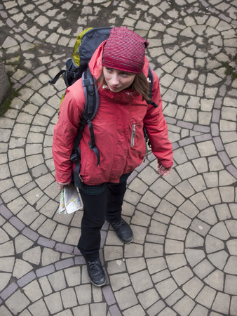 A lonely girl with a backpack and a map of the walks around the old town.の写真素材