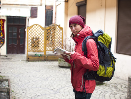 A lonely girl with a backpack and a map of the walks around the old town.の写真素材