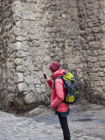 A young girl with a backpack and phone walking around the city.の写真素材