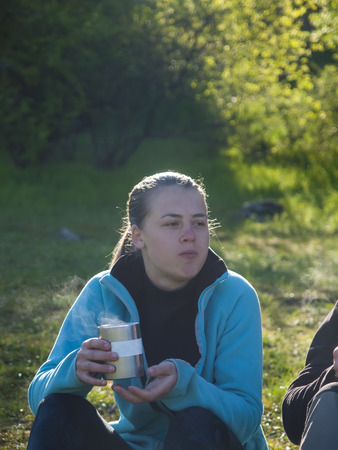 Girl drinking from mugs of hot in nature.の写真素材