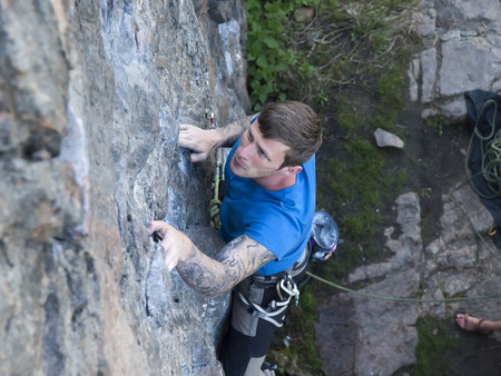 The man with the tattoos is engaged in rock climbing and climbs on the rock.の写真素材