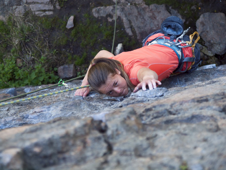 Strong girl climbs the mountain with the support of his friends.の写真素材
