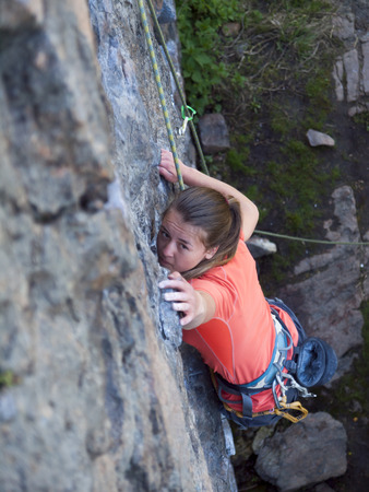 Strong girl climbs the mountain with the support of his friends.の写真素材