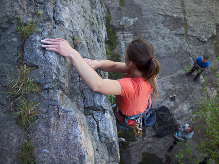 Young and beautiful girl climbed on a difficult wall.の写真素材