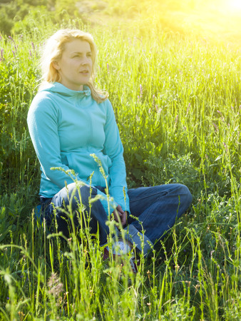 A young girl is sitting on green grass and dream.の写真素材