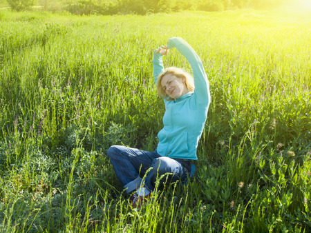 A young girl is sitting on green grass and dream.の写真素材