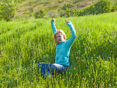 Portrait of young beautiful girl in a green field at sunset.の写真素材