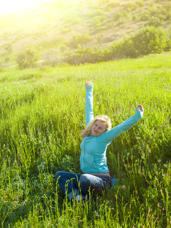 Portrait of young beautiful girl in a grassy field at sunset after waking up.の写真素材