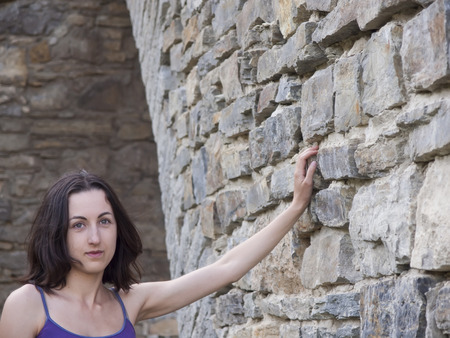 Beautiful brunette with a sad face standing alone near the wall.の写真素材