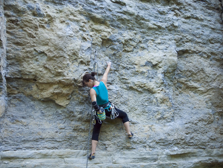 A young woman with a rope engaged in the sports of rock climbing on the rock.の写真素材