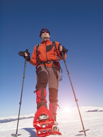 A man in snowshoes and a backpack is in the mountains in the snow.の写真素材