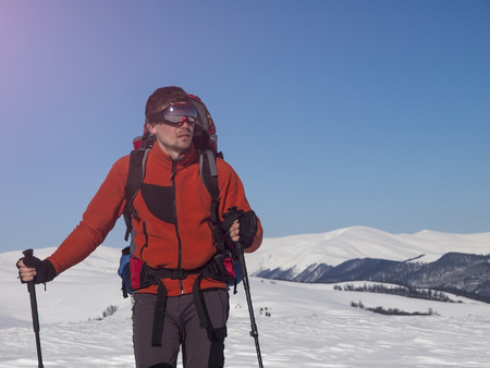 Man with glasses and a backpack is in the mountains in the snow.の写真素材
