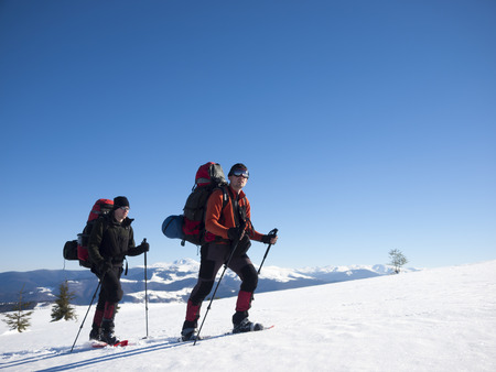 Friends in snowshoes and big backpacks are traveling through the mountains in winter.の写真素材
