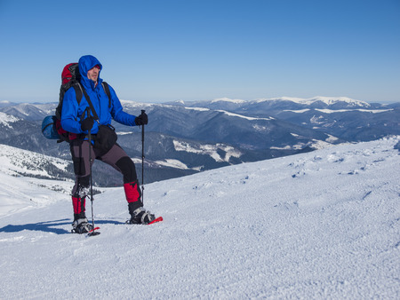 The man with the backpack and snowshoe travels through the mountains in winter.の写真素材
