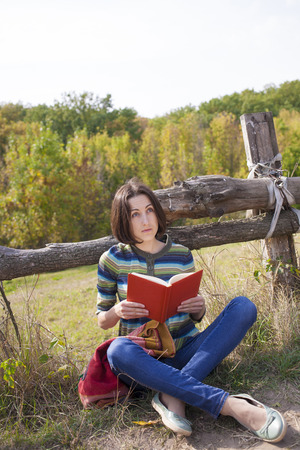Girl with books and backpack sitting in the Park.の写真素材