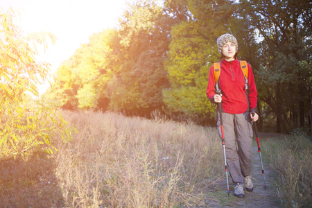 Woman with a backpack walking along the road in the woods.の写真素材
