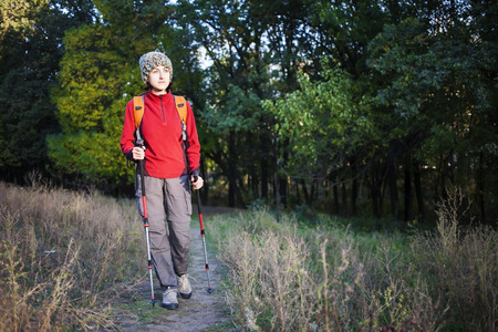 Woman with a backpack walking along the road in the woods.の写真素材
