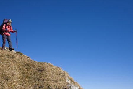 The girl descends from the high mountains on the background of blue sky.の写真素材