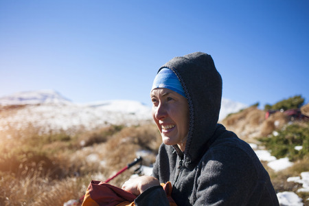Portrait of a young woman on the sky background and snowy mountains.の写真素材