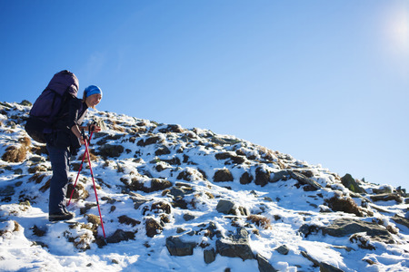 The girl with the rucksack moves along a mountain trail.の写真素材