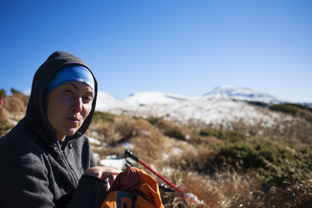 Portrait of a young woman on the sky background and snowy mountains.の写真素材