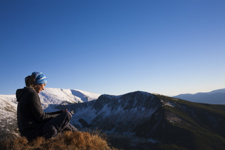 The girl meditates on a background of snowy mountains.の写真素材