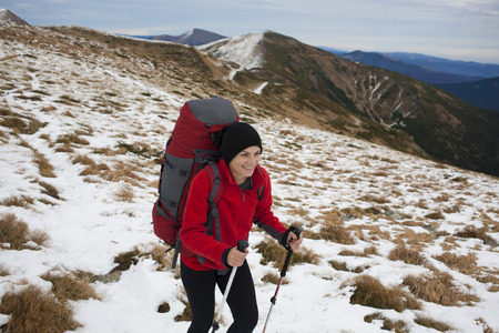 Girl with a backpack climbs to the top of a high mountain.の写真素材
