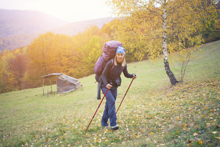 The girl with the backpack is walking through the autumn woods.の写真素材