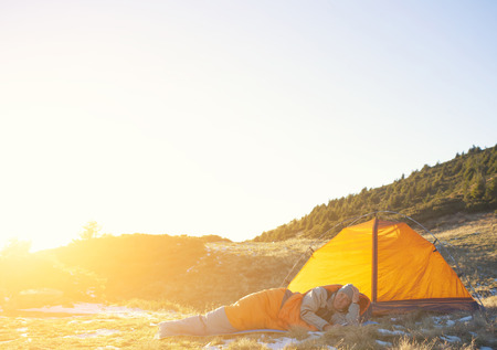 Girl lying in a sleeping bag on a background of tents.の写真素材