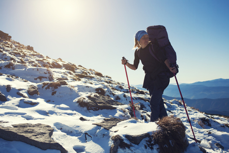 Beautiful woman with a backpack climbs the hill.の写真素材