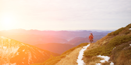 The girl with the rucksack moves along a mountain trail.の写真素材