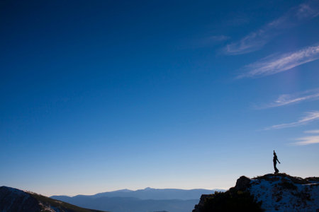 The silhouette of a man in the mountains against the blue sky.