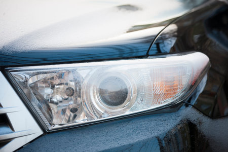 Car headlight covered with snow at close range.