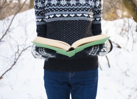 Girl in a wool sweater holding an old book.の写真素材