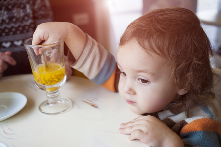 Mom gives little boy taste sea-buckthorn drink.の写真素材