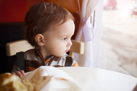 Portrait of a little boy who sits at the table and smiles.の写真素材