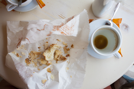 Empty coffee Cup and the remains of biscuits are on the table.の写真素材
