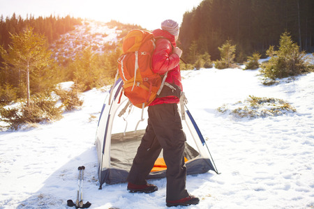 Climber with a backpack near the tent packing.の写真素材