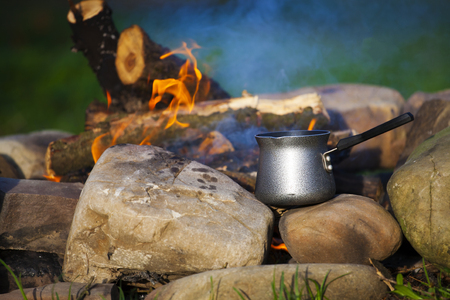 The maker stands near a bonfire in a clearing for camping.の写真素材