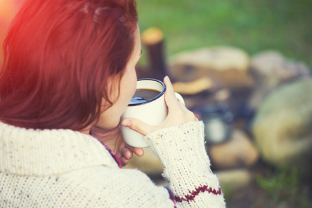 People sitting near the fire and drinking coffee.の写真素材
