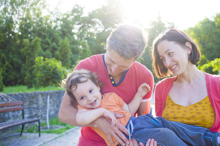 Young family playing with a small child on the walk in the Park.の写真素材