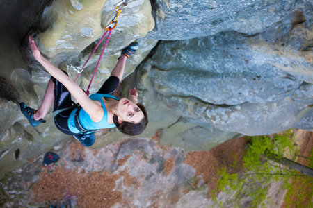 Girl rock climber climbs difficult route on the cliffs.