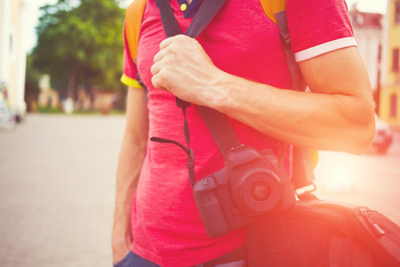 A man with a camera and a red t-shirt standing in the city.の写真素材