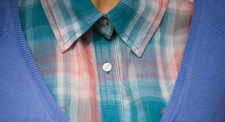 The girl dressed in a plaid shirt and blue sweater.の写真素材