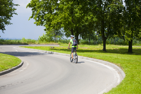 A man on a Bicycle with a backpack riding on an asphalt road in the journey.の写真素材