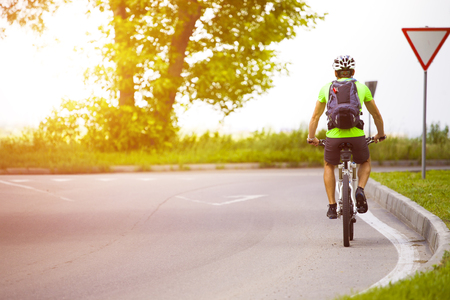 A man on a Bicycle with a backpack riding on an asphalt road in the journey.の写真素材