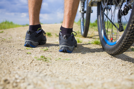 The cyclist is standing near his bike before a trip to the mountains.の写真素材