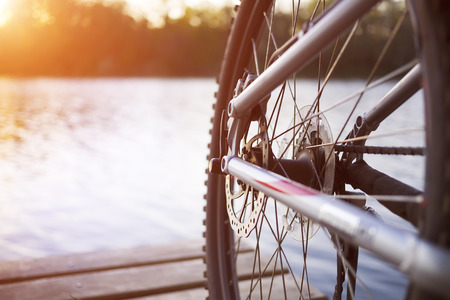 Bike stands on the dock near the river during sunset.の写真素材